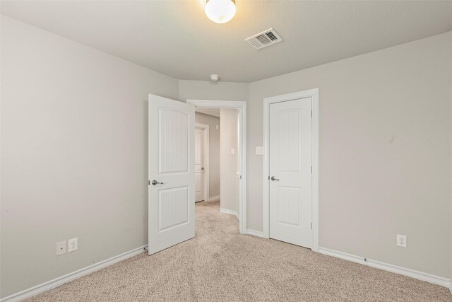 interior space with visible vents, baseboards, and light carpet