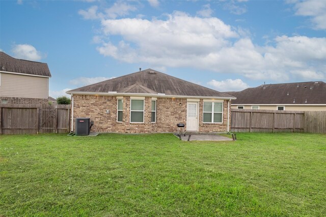 rear view of property with brick siding, a fenced backyard, a patio area, and a lawn