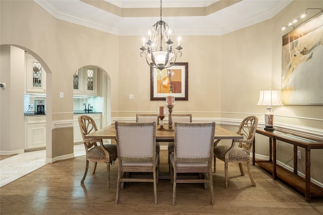 8010 Fonthill Dr, Spring, TX 77379 - dining area with ornamental molding, light wood-type flooring, a raised ceiling, a chandelier, and arched walkways