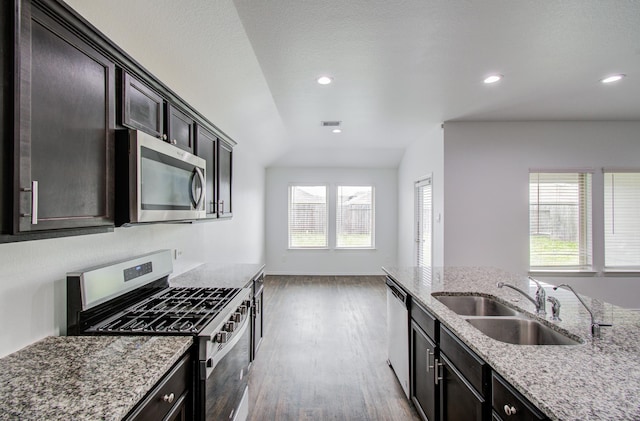 kitchen with wood finished floors, light stone countertops, recessed lighting, a sink, and stainless steel appliances