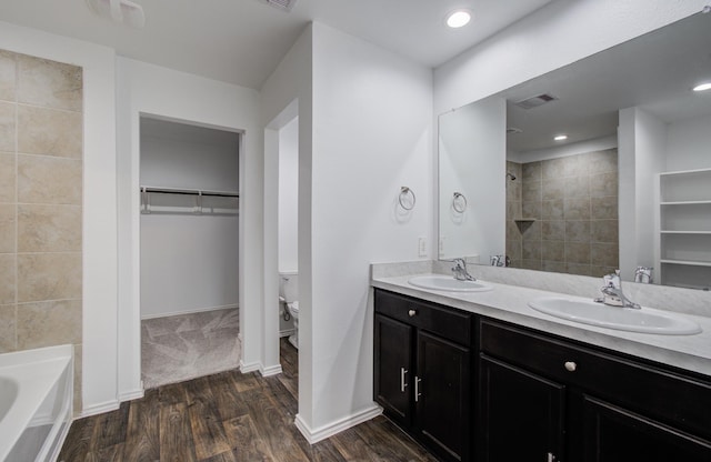 bathroom with visible vents, a sink, a garden tub, and wood finished floors