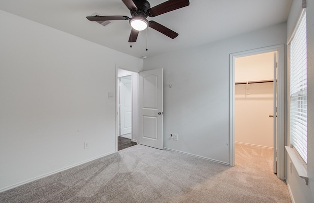 unfurnished bedroom with a closet, a walk in closet, carpet flooring, and visible vents