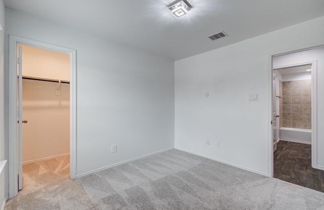 unfurnished bedroom with visible vents, baseboards, carpet floors, and a spacious closet