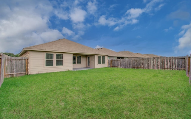 back of house with a fenced backyard, a patio, and a yard