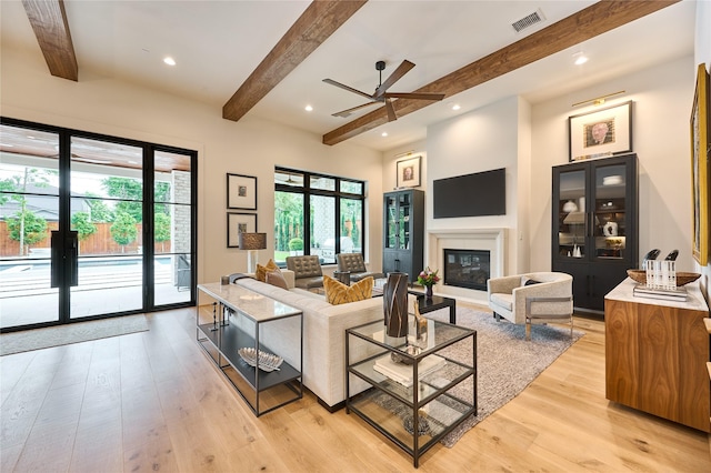 living area with light wood-type flooring, beam ceiling, visible vents, and plenty of natural light