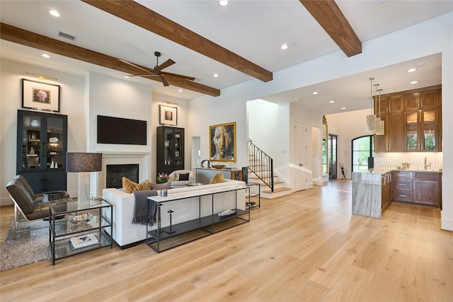 living room with stairs, visible vents, recessed lighting, light wood finished floors, and beamed ceiling