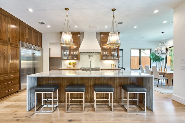 kitchen with a kitchen breakfast bar, decorative backsplash, built in fridge, custom exhaust hood, and recessed lighting