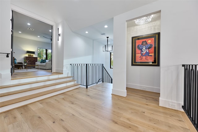 interior space with an upstairs landing, recessed lighting, a chandelier, light wood-style flooring, and baseboards
