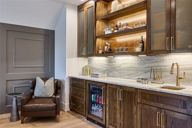bar with a sink, tasteful backsplash, a dry bar, wine cooler, and light wood-style flooring