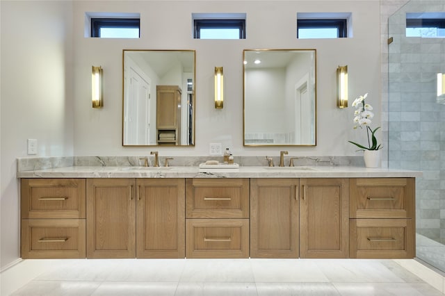 bathroom with a tile shower, double vanity, and a sink