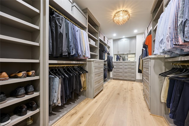 walk in closet with an inviting chandelier and light wood-style floors