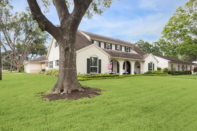 view of front facade featuring a porch, roof with shingles, and a front lawn