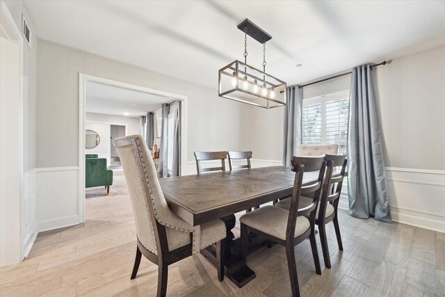 dining space featuring a wainscoted wall, light wood-style flooring, and visible vents