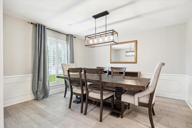 dining room with a decorative wall, a wainscoted wall, and light wood-style floors