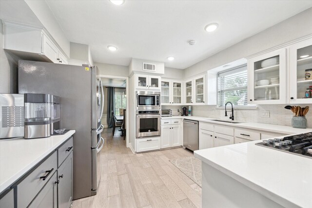 kitchen with visible vents, light wood-style floors, white cabinetry, a sink, and appliances with stainless steel finishes
