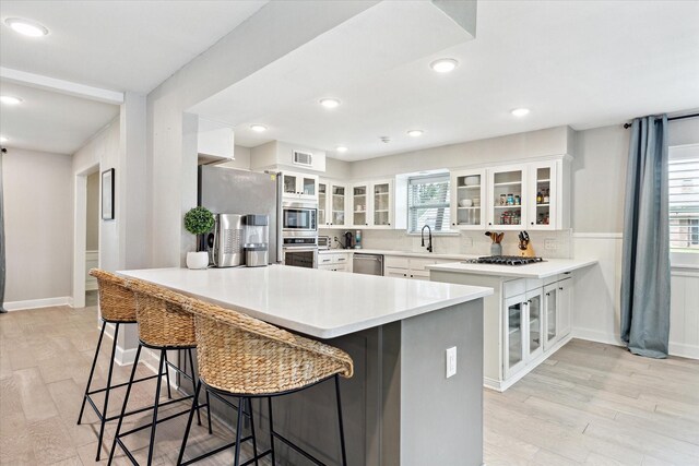 kitchen featuring appliances with stainless steel finishes, light wood-style floors, a peninsula, a kitchen bar, and visible vents