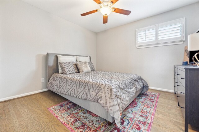 bedroom featuring a ceiling fan, baseboards, and light wood finished floors