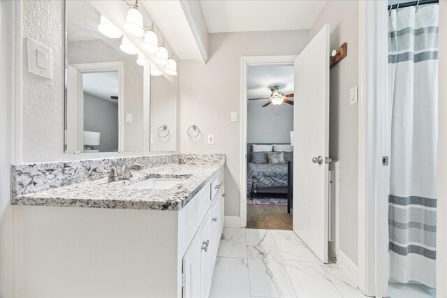 ensuite bathroom featuring connected bathroom, ceiling fan, vanity, marble finish floor, and baseboards