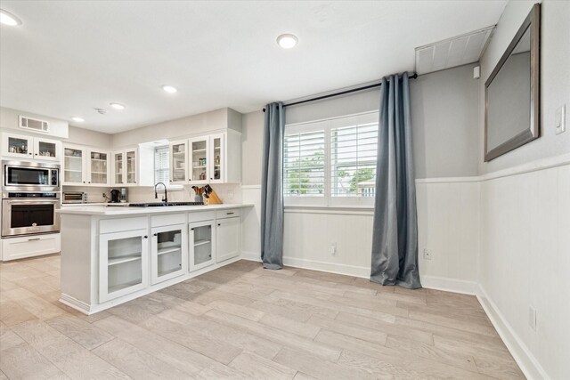 kitchen featuring a sink, appliances with stainless steel finishes, a wainscoted wall, and visible vents