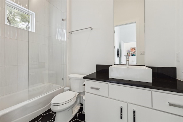 bathroom featuring toilet, bath / shower combo with glass door, and vanity