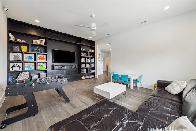 living room with a ceiling fan, visible vents, built in features, wood finished floors, and baseboards