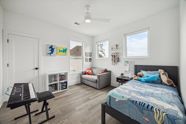 bedroom featuring baseboards, a ceiling fan, wood finished floors, and visible vents