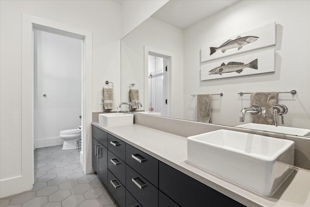 full bathroom with a sink, tile patterned flooring, toilet, and double vanity