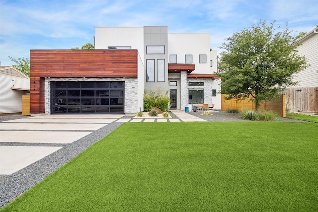 view of front of house featuring fence, stone siding, a front yard, and concrete driveway