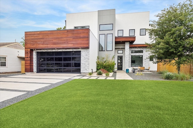 contemporary home with a garage, a front lawn, driveway, and stone siding
