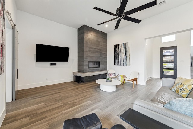 living area with ceiling fan, a large fireplace, recessed lighting, baseboards, and wood finished floors