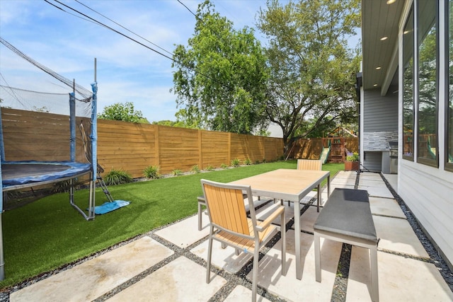 view of patio featuring a fenced backyard, outdoor dining area, and a trampoline