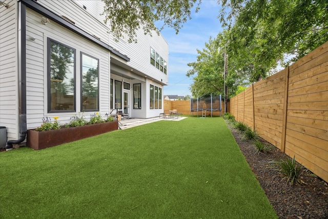 view of yard featuring a fenced backyard, a trampoline, and a patio area