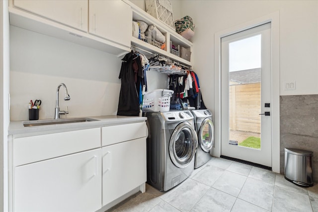washroom with a sink, light tile patterned floors, cabinet space, and washer and clothes dryer
