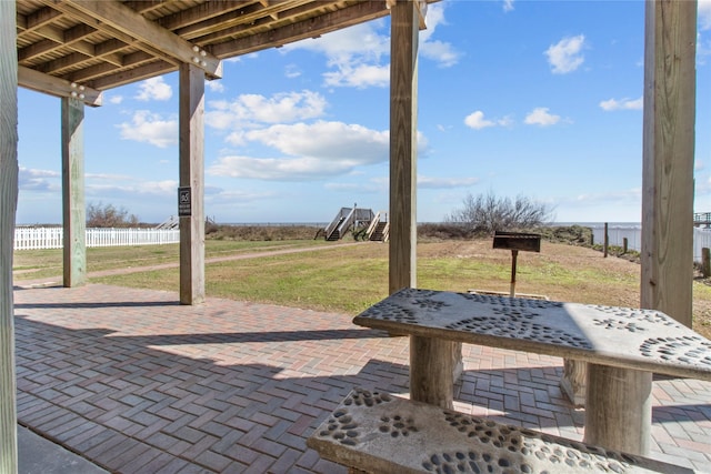 view of patio featuring a water view and fence