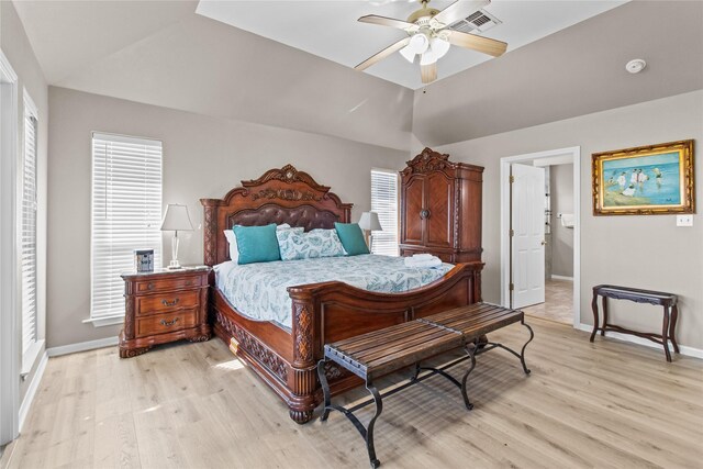 bedroom featuring baseboards, light wood finished floors, visible vents, and vaulted ceiling