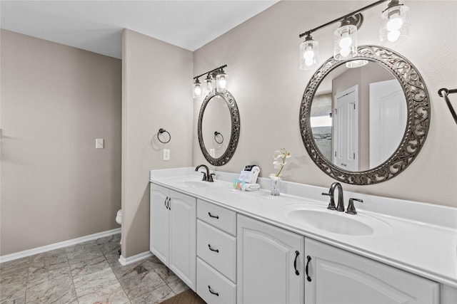 full bathroom with a sink, baseboards, toilet, and double vanity