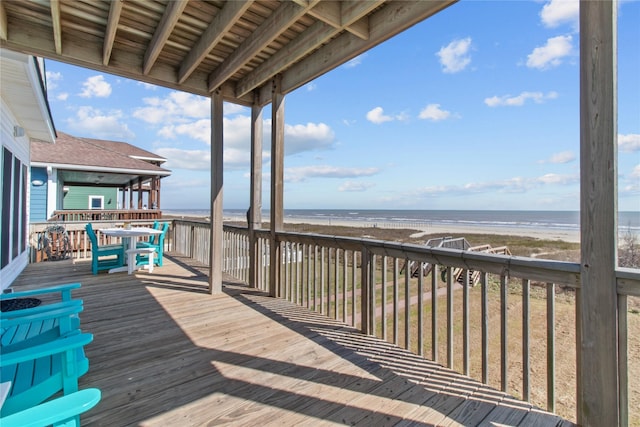 wooden terrace featuring a water view and a view of the beach