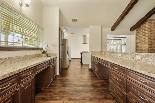 kitchen with appliances with stainless steel finishes, beam ceiling, wall chimney exhaust hood, dark wood-type flooring, and visible vents