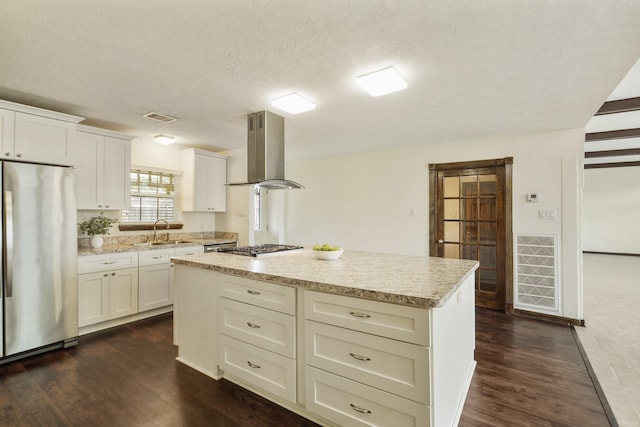 kitchen with exhaust hood, visible vents, a center island, a sink, and stainless steel appliances