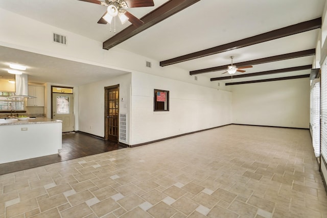 unfurnished living room with baseboards, ceiling fan, and visible vents
