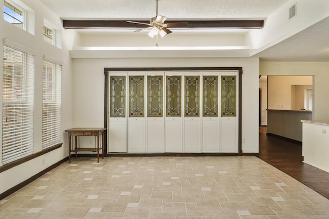 unfurnished bedroom featuring baseboards, beamed ceiling, and visible vents