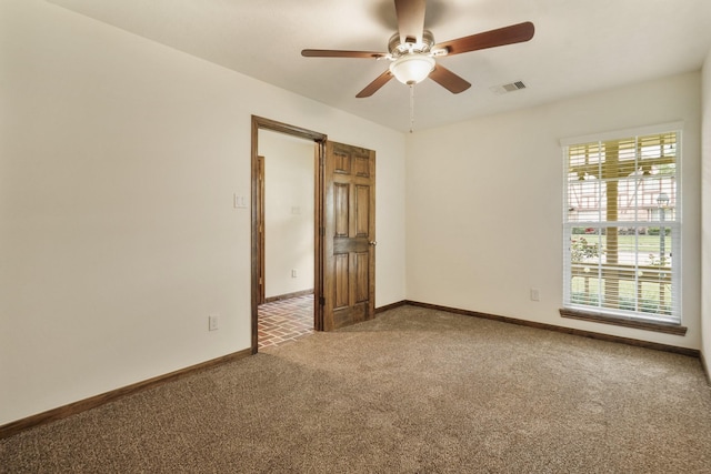 carpeted empty room with baseboards, ceiling fan, and visible vents