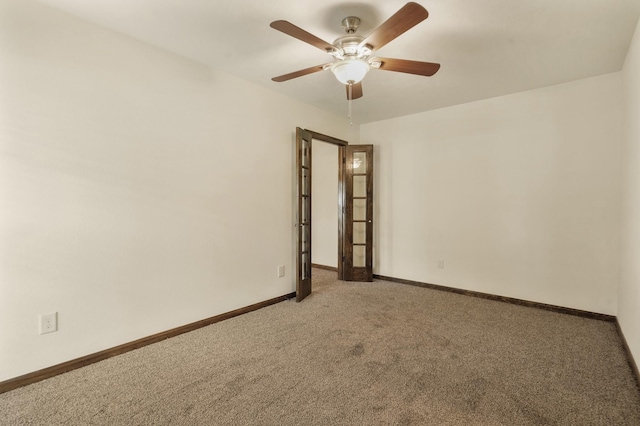 spare room with carpet flooring, a ceiling fan, and baseboards