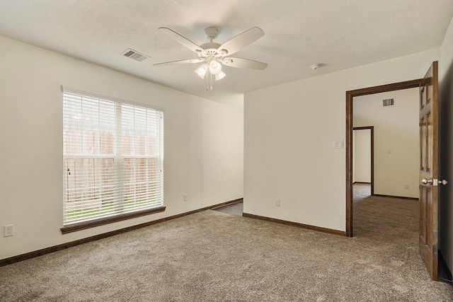 unfurnished room with carpet floors, visible vents, and plenty of natural light