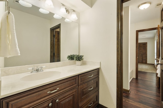 bathroom featuring baseboards, visible vents, wood finished floors, and vanity