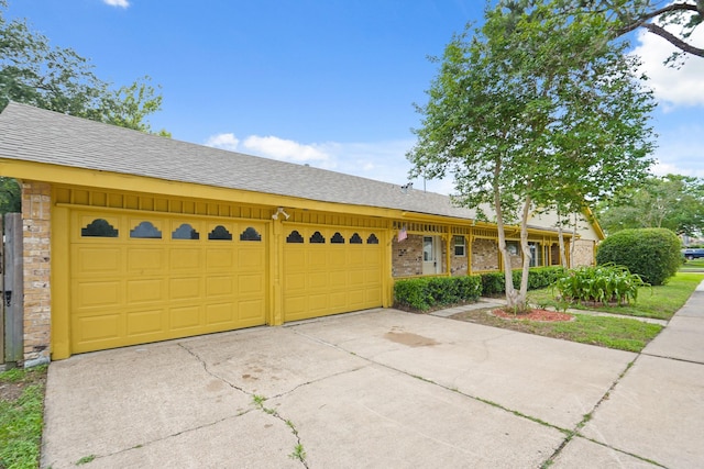 ranch-style house with brick siding, a garage, a shingled roof, and concrete driveway