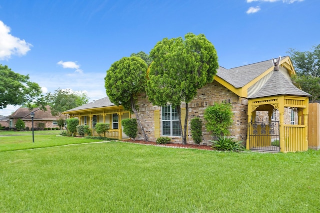 ranch-style house with brick siding, fence, roof with shingles, and a front lawn