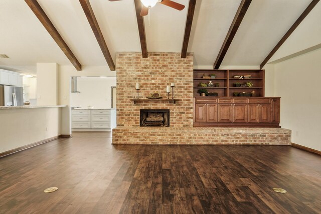 unfurnished living room featuring vaulted ceiling with beams, a ceiling fan, a brick fireplace, and dark wood-style floors