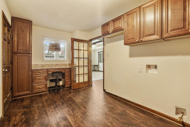 unfurnished office with baseboards, dark wood-style flooring, built in desk, and french doors