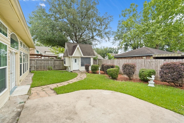 view of yard featuring a patio, a fenced backyard, and an outdoor structure